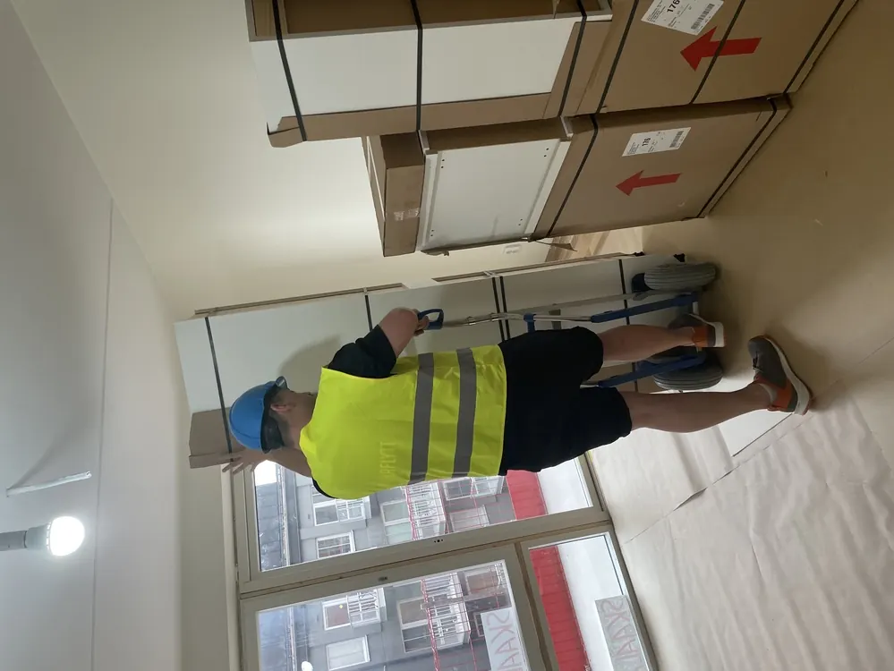 Flyttarbetare från Rent A Mover bär tunga möbler och kartonger under en företagsflytt i Stockholm.