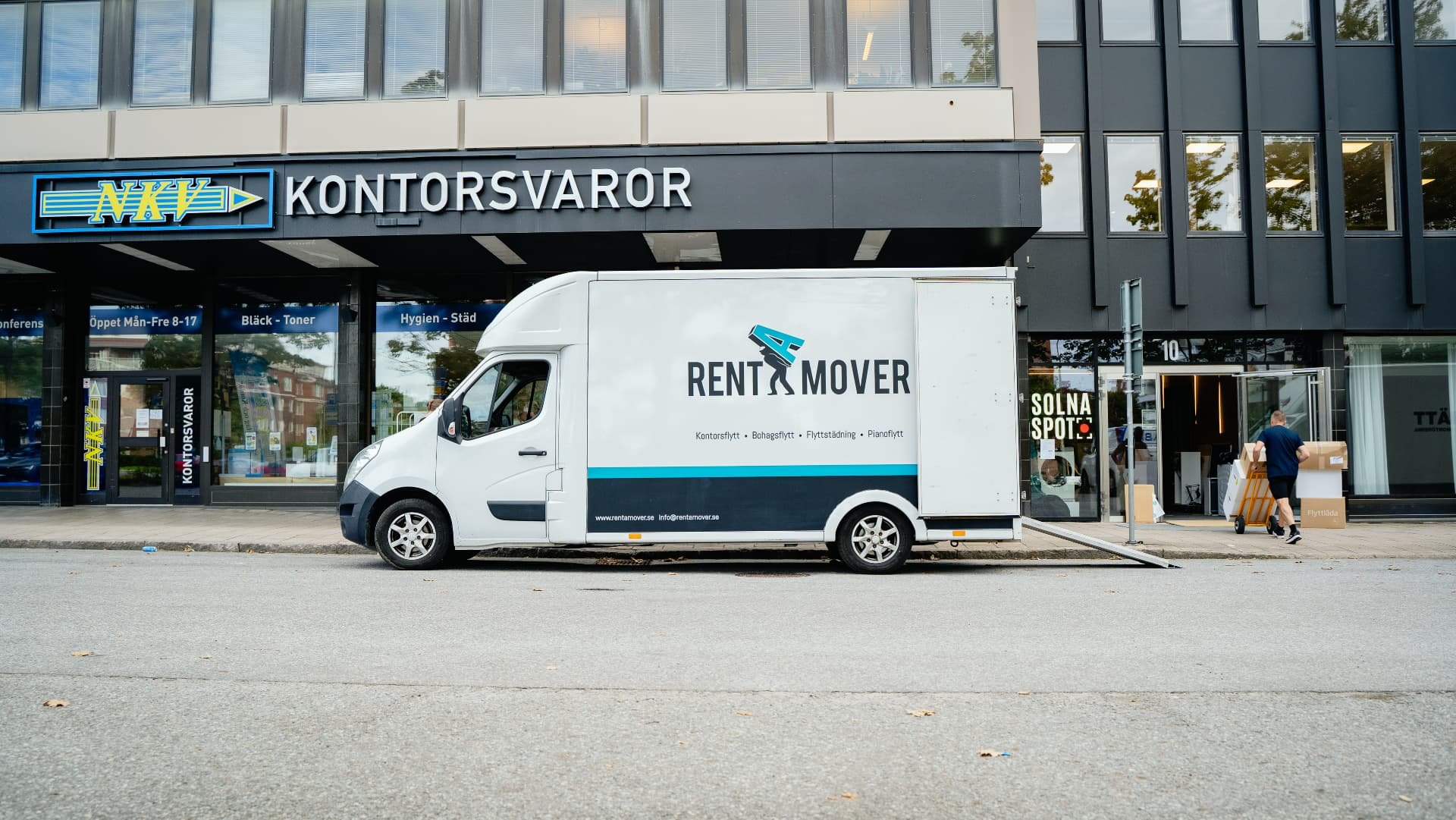 Rent A Movers flyttbil står parkerad utanför en kontorsfastighet i Solna under en kontorsflytt.